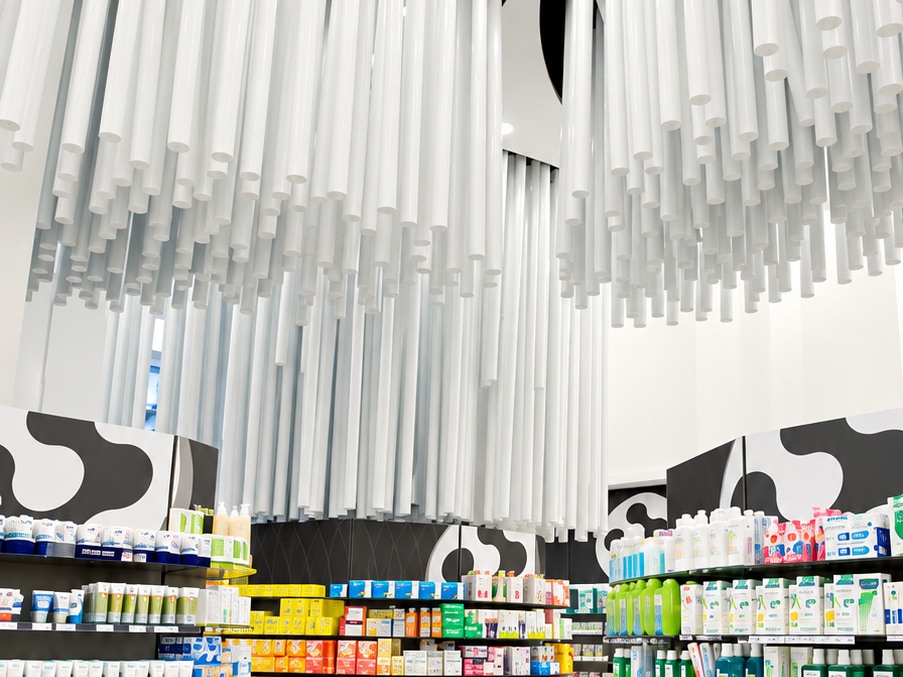 Interior de Farmacia Conde Lumiares con elementos suspendidos y mobiliario curvo