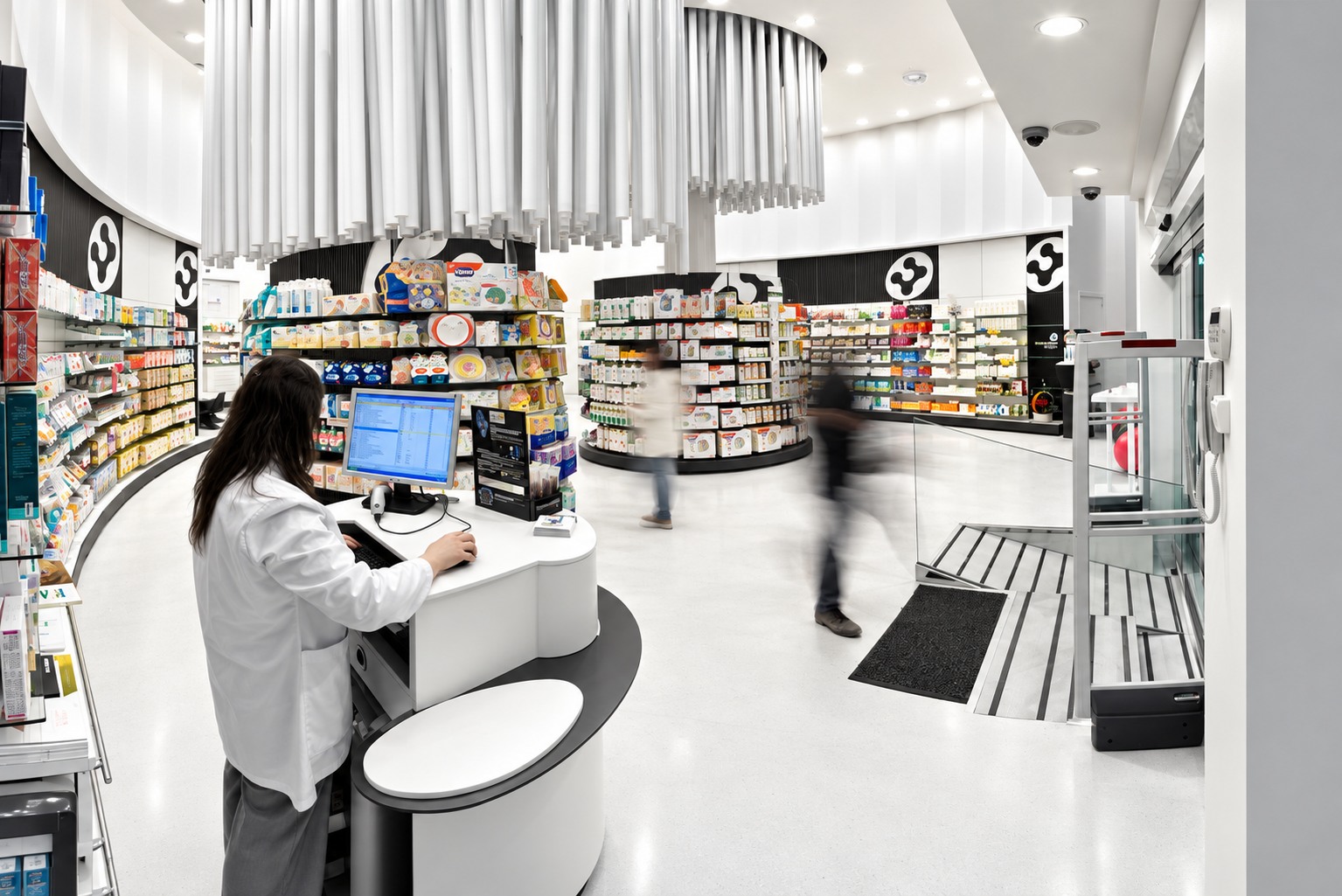 Interior de Farmacia Conde Lumiares con puesto de atención y recorrido entre expositores curvos