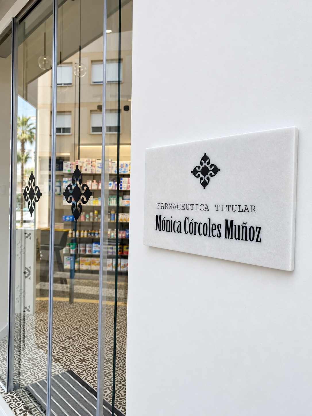 Placa de acceso de Mónica Córcoles Muñoz junto a la entrada de la farmacia