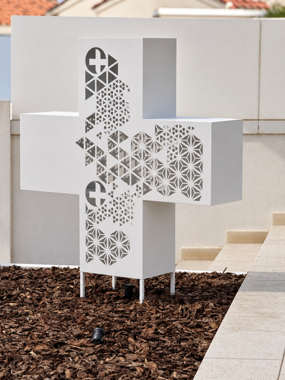 Escultura exterior metálica en forma de cruz diseñada para Farmacia ULM