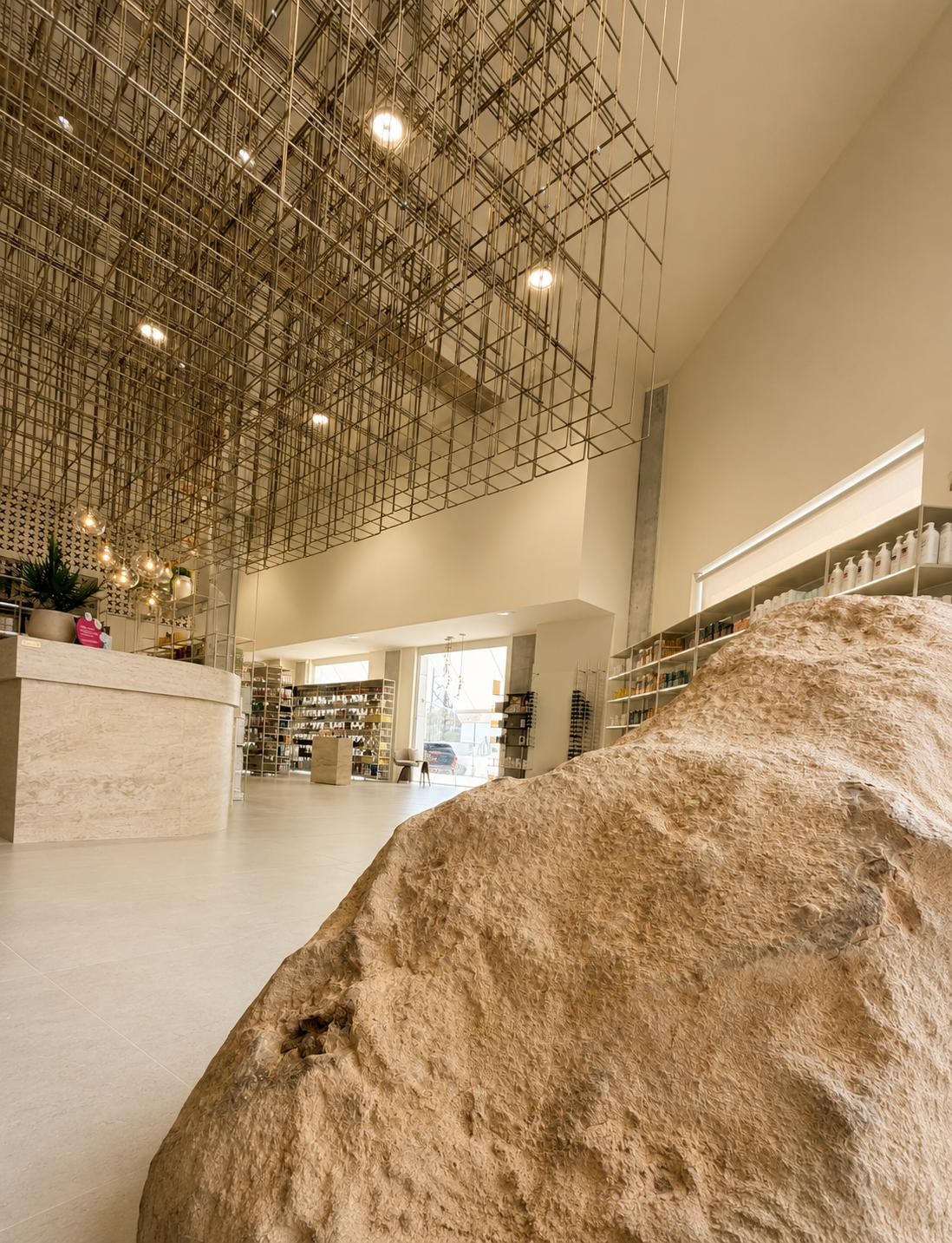 Interior de Farmacia Xenia con instalación escultórica metálica y elemento pétreo